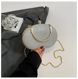 Detail of silver glitter oval evening bag with gold floral handle and crystal clasp