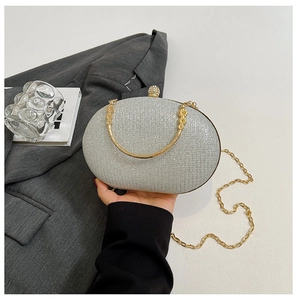 Detail of silver oval evening bag with glitter surface and floral carved gold handle