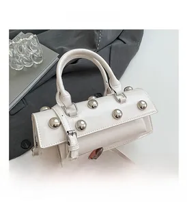 Gros plan d'un sac baguette en cuir blanc avec rivets argentés et poignées circulaires