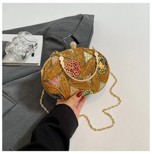Detail of luxury sequined evening clutch with golden leaf patterns and metal chain