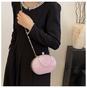Pink sequin evening bag with gold chain and crystal handle shown on a black dress