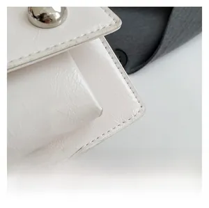 Détail macro du sac en cuir blanc montrant la texture fine et la boucle en métal argenté