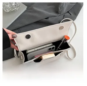 Vue intérieure du sac en cuir blanc cassé contenant un téléphone et un rouge à lèvres