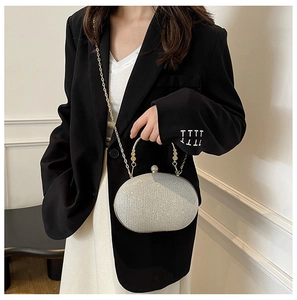 Silver sequin clutch bag with gold handle and chain strap shown with suit