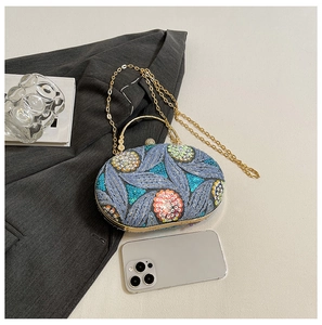 Detail of evening bag with intricate embroidery and gold handle next to a smartphone