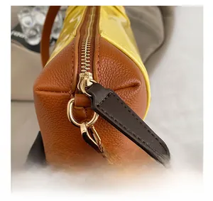 Detailed macro of smooth zipper with brown leather pull on yellow patent crossbody bag