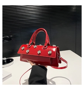 Détail du sac en cuir verni rouge avec clous argentés et poignée supérieure