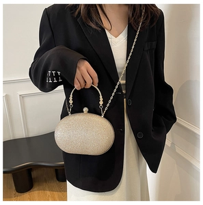 Detail of a sparkling gold glitter oval clutch bag with round handle and chain strap