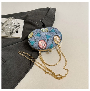 Detail of floral sequin embroidery and gold metal ring handle on blue evening clutch bag