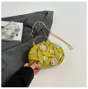 Detail view of yellow floral embroidery with sequins and beads on an oval evening clutch bag
