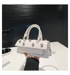 Gros plan d'un sac à main blanc avec rivets argentés et bandoulière amovible élégante