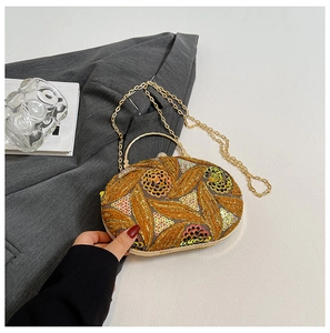 Detail of gold evening bag showing intricate leaf sequin embroidery and round metal handle