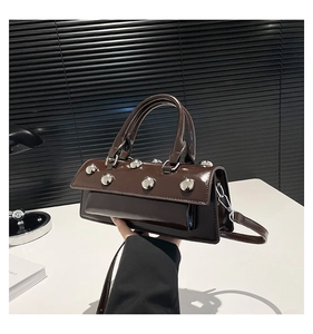 Détail du sac en cuir verni marron foncé avec rivets argentés et surface brillante