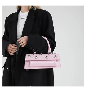 Détail du sac à main en cuir verni rose avec rivets sphériques argentés et design chic