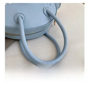 Detailed macro view of light blue leather handbag handles with premium gold metal zippers