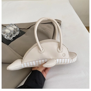 Detailed view of creative dolphin-shaped handbag in beige PU leather with striped accents