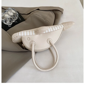 Detail of creative cream whale-shaped handbag showing stereo fins and PU leather texture