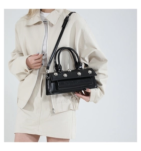 Vue détaillée du sac baguette en cuir verni noir avec cinq clous métalliques argentés