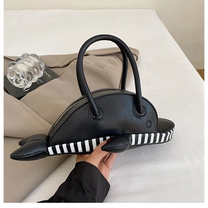 Detail of whale-shaped black leather handbag with striped base and sturdy handle