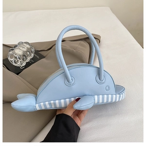 Detail view of a creative whale-shaped handbag in light blue leather and striped fabric