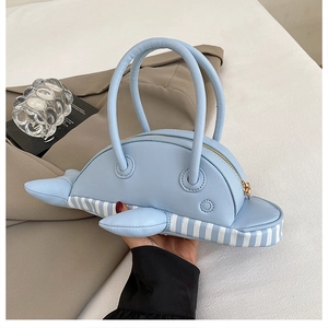 Detail showing the light blue dolphin-shaped handbag with vertical striped textures and fins