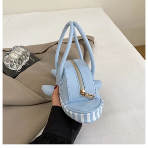 Detail of light blue shark-shaped handbag featuring premium leather and gold zipper