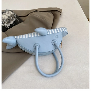 Detail showing the light blue whale-shaped handbag with premium PU leather and 3D fin design