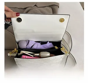 Internal view of a white marble pattern chain bag showing phone, umbrella and cosmetics