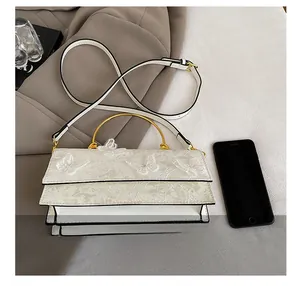 Detailed view of white lace handbag with butterfly embroidery and golden metal handle