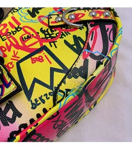 Macro view of street graffiti pattern on yellow leather bag with silver metal D-ring hardware