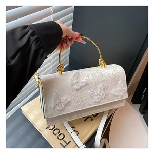 Détail d'un sac à bandoulière blanc avec broderie papillon délicate et poignée en anneau doré