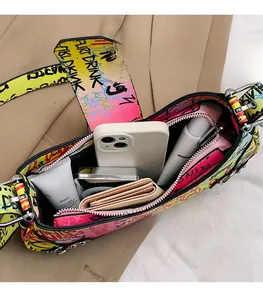 Close-up showing internal storage space of the graffiti print shoulder bag with essentials