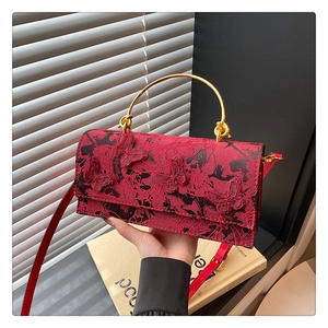 Détail du sac bandoulière en dentelle rouge avec papillons et poignée en métal doré