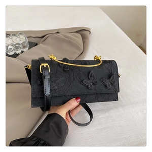Détail du sac noir avec broderie papillon et poignée en métal doré élégante