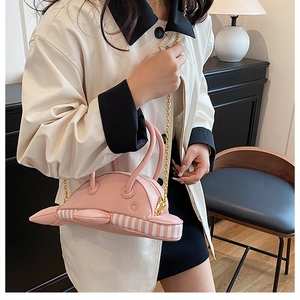 Detail of pink dolphin-shaped crossbody bag with gold chain and striped side accents