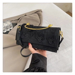 Détail de broderie en dentelle fleurie et papillon sur un sac à main noir élégant