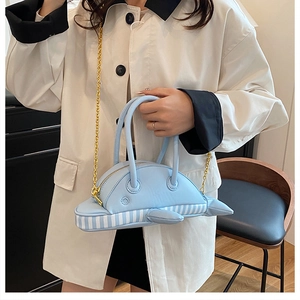 Detail of cute dolphin-shaped blue shoulder bag with golden chain and striped pattern