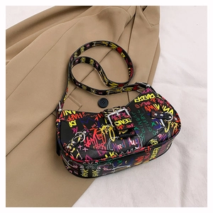 Detail of colorful graffiti print and silver buckles on this black leather hobo bag