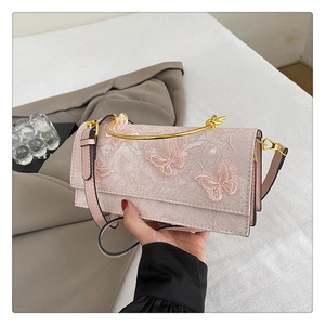 Détail du sac rose en dentelle avec broderie florale et poignée en métal doré