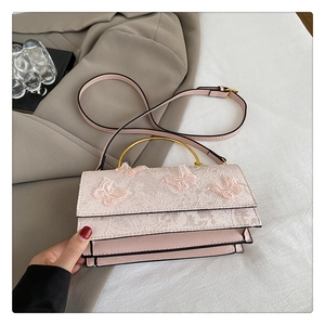 Détail d'un sac rose avec dentelle, appliques papillon et poignée anneau dorée