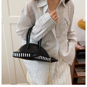 Detail of unique black hat-shaped handbag with striped trim and gold chain strap