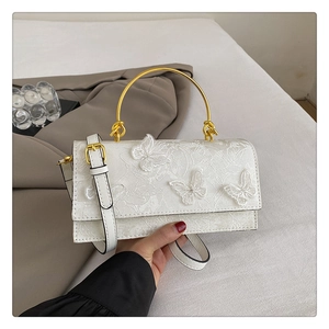 Détail de la texture en dentelle blanche et des broderies papillons 3D sur le sac à main