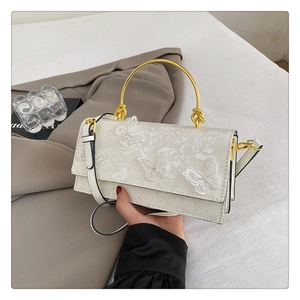 Détail d'un sac en cuir blanc avec dentelle florale et broderie de papillons en relief