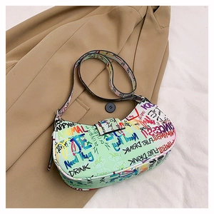 Detail of colorful graffiti print shoulder bag with adjustable strap on khaki coat