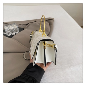 Détail du sac en cuir blanc gaufré avec poignée dorée semi-circulaire et bandoulière amovible
