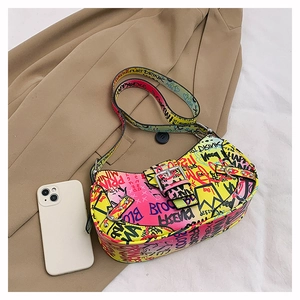 Detail view of graffiti print crossbody bag next to a smartphone for size reference