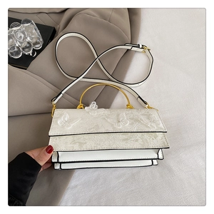 Détail de la broderie papillon blanche et poignée en métal doré sur le petit sac