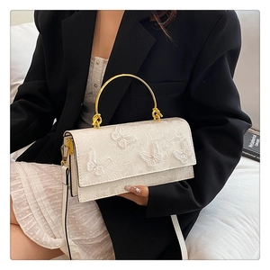 Détails des papillons en dentelle 3D sur un sac rectangulaire à bandoulière crème