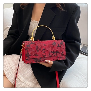Détail du sac rouge avec relief papillon en 3D et poignée en métal doré élégant