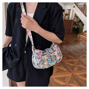 Detailed side view of colorful graffiti crescent hobo bag worn by model in dark blazer